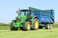 John deere green tractor pulling a trailer in grass field Royalty Free Stock Photo