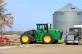 A John Deere 9470R farm tractor with a disc on the back sitting in a farm yard