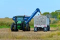 John Deere 8345R tractor unloading corn from a grain wagon for transport