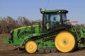 John Deere Track Tractor in a farm field with blue sky out in the country.