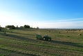 John Deere Tractor 6715R with John Deere V461R round baler making Hay Bales in an agricultural field. Farm Round Hay Bale Tractor Royalty Free Stock Photo