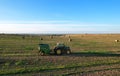 John Deere Tractor 6715R with John Deere V461R round baler making Hay Bales in an agricultural field. Farm Round Hay Bale Tractor Royalty Free Stock Photo