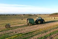 John Deere Tractor 6715R with John Deere V461R round baler making Hay Bales in an agricultural field. Farm Round Hay Bale Tractor Royalty Free Stock Photo