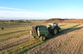 John Deere Tractor 6715R with John Deere V461R round baler making Hay Bales in an agricultural field. Farm Round Hay Bale Tractor Royalty Free Stock Photo