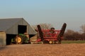 A John Deere tractor with a Sunflower oneway disc on the back with tree`s and blue sky with a barn.