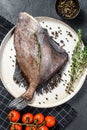 John Dory fish with pink pepper and thyme. Black background. Top view Royalty Free Stock Photo