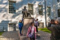 John Harvard statue and passers-by and visitors outside Harvard University