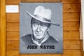 John Wayne portrait hanging on wooden wall