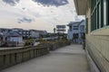 Johnnie Mercer\'s Fishing Pier with homes, parked cars and people walking, blue sky and clouds in Wrightsville Beach