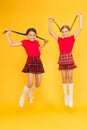 Join celebration. School uniform. Scottish style. Cheerful friends schoolgirls jumping yellow background. Celebrate