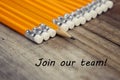 JOIN OUR TEAM inscription. Yellow office pencils over rustic wooden table.