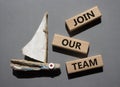 Join our team symbol. Wooden blocks with words Join our team. Beautiful grey background with boat. Business and Join our team Royalty Free Stock Photo