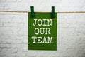 Join Our Team text on paper card hanging with rope on white brick background Royalty Free Stock Photo