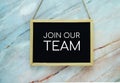 Join Our Team typography text on wooden blackboard hanging on marble background Royalty Free Stock Photo