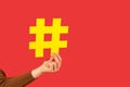 Join popular blog! Closeup of female hand holding big yellow hashtag sign, sharing tagged message, recommending follow trends