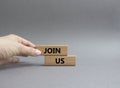 Join us symbol. Concept word Join us on wooden blocks. Beautiful grey background. Businessman hand. Business and Join us concept.