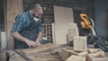 Joiner labouring in mask and glasses for safety. Carpenter with chisel