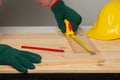 Joiner measuring a wooden plank with tape measure yellow on the work-table for construction
