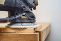 Joiner tools. Sanding a wooden board with a hand-held electric sander