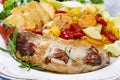 Joint of pork with baked potatoes and fresh vegetables Royalty Free Stock Photo