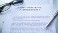 Joint venture agreement lying on table, pen and eyeglasses on official document Royalty Free Stock Photo