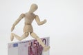 Jointed doll jumping over a 500-Euro-Banknote Royalty Free Stock Photo