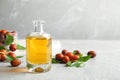 Jojoba oil in glass bottle and seeds on light table