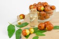 Jojoba oil in a transparent bottle on a wooden table. Fresh fruits and jojoba oil