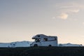 JOKULSARLON, ICELAND - AUGUST 2018: Campervan parked at black beach at sunset with snow capped glacier in the background