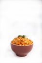 Jollof rice with parsley in a ceramic cup on a white background. National cuisine of Africa. Copy spaes