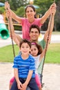 Jolly caucasian family swinging in the park