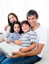 Jolly family using a laptop sitting on sofa