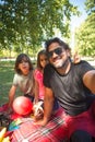 Jolly father with disability taking selfie with kids on picnic