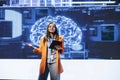 Jolly presenter talking at AI expo using mic and tablet
