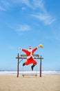 Jolly Santa Claus enjoying a day at the beach while seated in a swing.