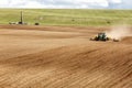 A John Deere tractor pulling a plowing implement, plows an Idaho farm field