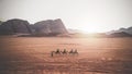 Jordan, Wadi Rum. Caravan of camels with drovers in the desert, rock mountains at sunset Royalty Free Stock Photo