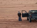 Old bedouin stands near pickup truck in Wadi Rum desert in Jordan