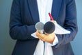 Journalist at media event or news conference, holding microphone, writing notes. Broadcast journalism concept. Royalty Free Stock Photo