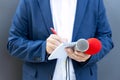 News reporter at press conference or media event, holding microphone, writing notes. Broadcast journalism concept Royalty Free Stock Photo