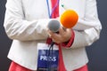 Journalist at news conference, writing notes, holding microphone