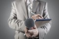 Journalist at a news press conference or media event holding a microphone and writing notes Royalty Free Stock Photo