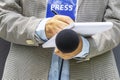 Journalist with press pass or media accreditation at news event, holding microphone, writing notes Royalty Free Stock Photo