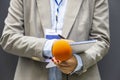 Journalist correspondent or reporter at media event, holding microphone, writing notes