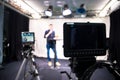 Journalist in a television studio is talking into a microphone, blurry film cameras