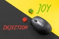 Joy as an alternative to dejection, a way out of depression concept. PC mouse and cheerful and sad emoticons on yellow