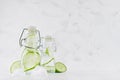 Joy bright fresh summer drinks with green cucumber, ice cubes, soda water in two elegant yoke bottles on soft light white wood. Royalty Free Stock Photo