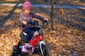 Joy child with a pink bike in the autumn park and bright colorful foliage