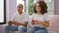 Joy-filled beautiful couple enjoy playing video game on their comfortable sofa, exuding confidence and happiness in the heart of