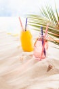 Joy fun summertime beach vacation with blue sea -  cold cocktails in glass bottles with ice, straw, sun hat under green palm leaf. Royalty Free Stock Photo